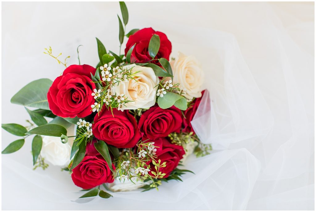 Red and white rose bridal bouquet styled on bridal veil